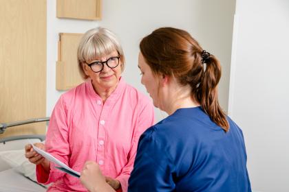 Patient och sjukskötare sitter på sängen.