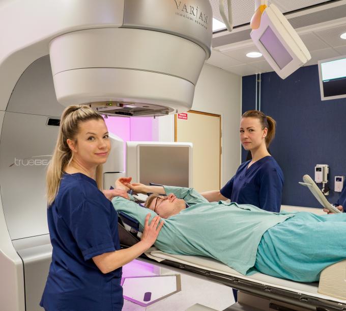 Three nurses and a patient at the imaging device.